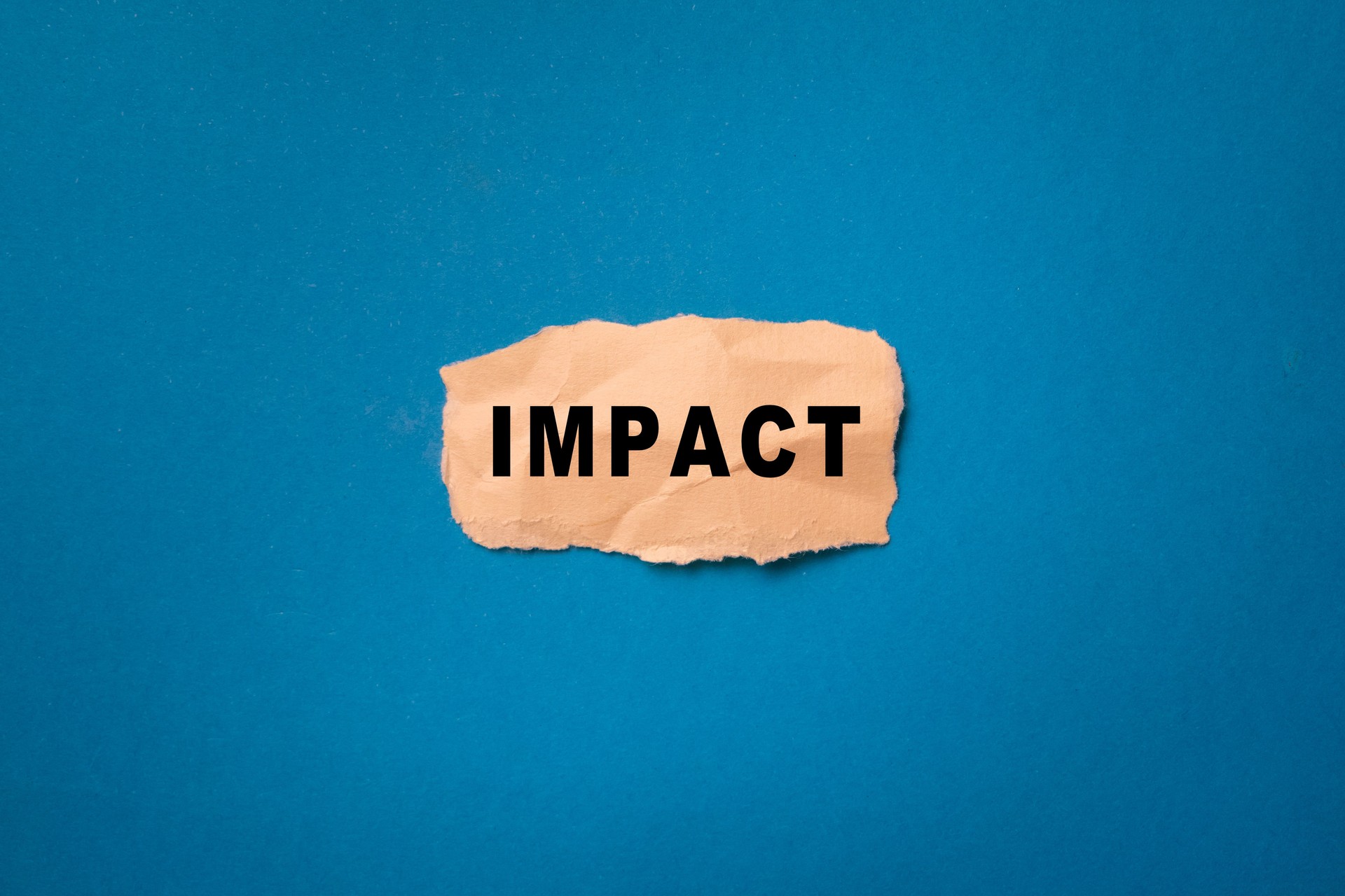 impact word text message on torn paper on blue background